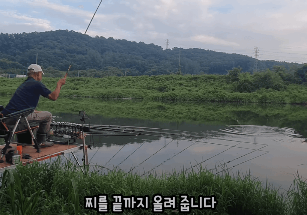 무한천 강가에서 낚싯대를 드리우고 있는 낚시인, 찌가 시원하게 솟아오르는 순간