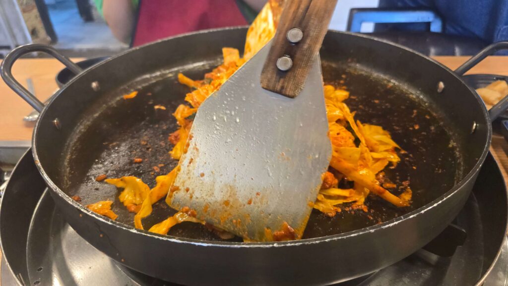 "조리 중인 닭갈비가 반쯤 익어가며 불판 위에 펼쳐진 장면"