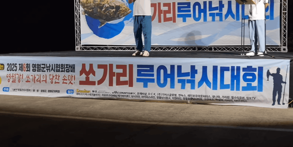 영월쏘가리낚시대회 무대 전경, ‘쏘가리 루어낚시대회’ 현수막 앞에서 참가자가 대형 쏘가리 모형을 들고 시상식에 참여하는 모습.