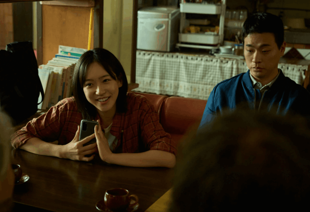 카페에서 휴대전화를 들고 웃음 짓는 젊은 여성