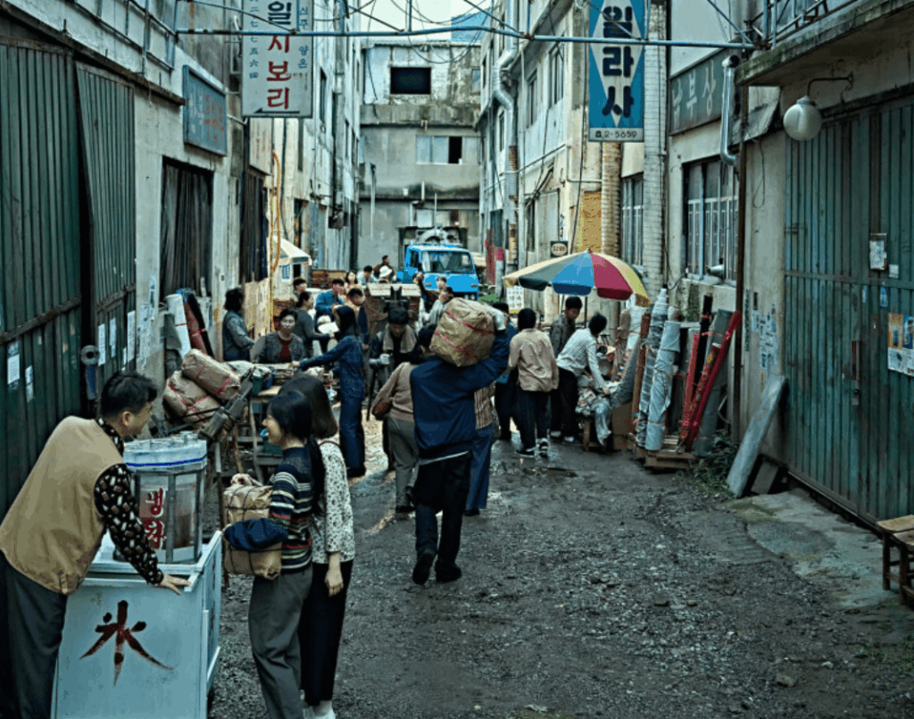 좁은 골목에서 사람들이 모여 활기차게 움직이는 시장 풍경